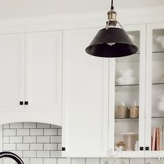 a kitchen with white cabinets and black lights above the stove top, along with an island sink