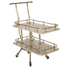 three tiered serving cart with marble top and brass handles on casteors, in the style of art deco