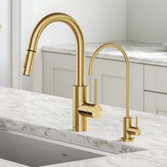 a kitchen sink with gold faucet and marble counter top