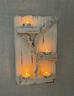 a wall mounted candle holder with three lit candles