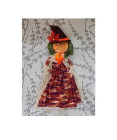 an orange and brown doll with a black hat on it's head sitting on a bed