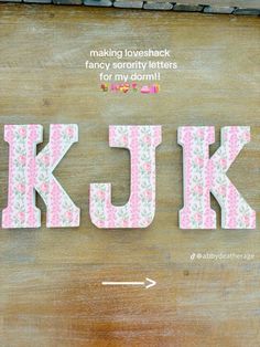 the letter k is made out of fabric and has pink flowers on it, along with an arrow