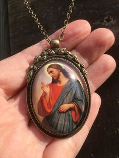 Beautiful pendant of Jesus Christ. The pendant is approx. 2,2 x1,6 inch (5,5 x 4 cm) and is set in a leadfree antique brass setting. The necklace is a very fine leadfree antique brass metal chain (length approx. 42cm). Due to the shape of the glass cabochon the light is reflected, so the real pendant is much more beautiful than the picture. The pendant is delivered in a nice gift pouch. Please feel free to follow me on Pinterest and instagram! Cross Pendant Jewelry As A Gift, Cross Shaped Large Pendant Jewelry For Gift, Cross-shaped Jewelry With Large Pendant As Gift, Cross-shaped Large Pendant Jewelry For Gift, Spiritual Round Pendant For Gift, Engraved Cross Pendant Necklace As Gift, Bronze Jewelry With Adjustable Chain For Gift, Cross Pendant Locket Jewelry For Gift, Cross Pendant Locket Jewelry Gift