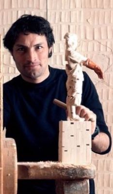 a man sitting in front of a wooden sculpture