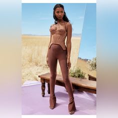 a woman standing in front of a mirror wearing high heeled boots and a bodysuit