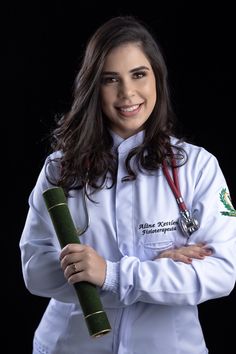 a woman in white lab coat holding a large green pipe and smiling at the camera