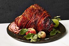 a large piece of meat sitting on top of a plate next to apples and leaves