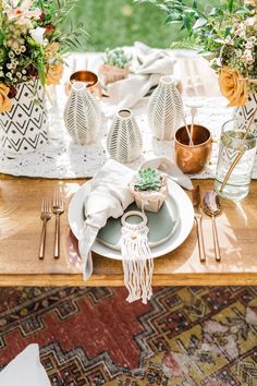 the table is set with white plates, silverware and succulents