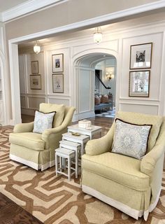 a living room with two chairs and a coffee table in front of a doorway that leads to another room