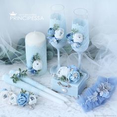 blue wedding decorations with candles and flowers on white lace table cloth, surrounded by other items