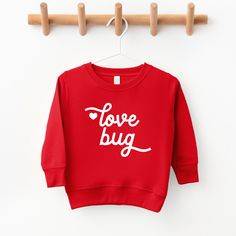 a red sweatshirt with the words love bug on it hanging from a wooden hanger