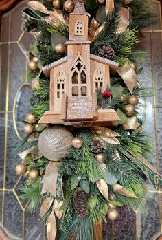 a christmas wreath with a birdhouse and pine cones