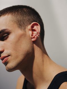 a man with ear piercings on his ears looking off to the side in profile