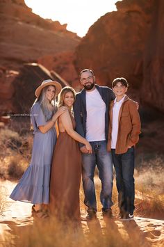 a family posing for a photo in the desert at sunset with mountains and rocks behind them