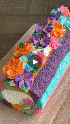 a cake with flowers on it sitting on top of a wooden table