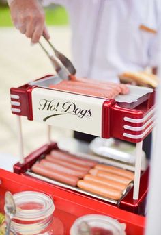 a hot dog stand with sausages and ketchup on it's grill