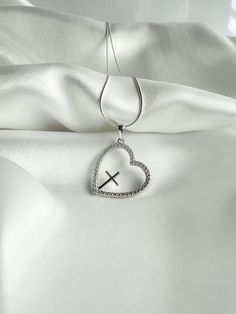 Showcase your faith with the Chrissie Silver Necklace. Made of sterling silver, this elegant piece features a delicate cross nestled within a heart, symbolizing your devotion. Perfect for any occasion, it's a timeless reminder of your beliefs. Product Details Materials: 925 Sterling Silver, Cubic Zirconia Size: Necklace 20 inches, Heart 20mm Sterling Silver Cross Pendant Necklace For Wedding, Personalized Sterling Silver Cross Pendant Necklace, Personalized Sterling Silver Pendant Cross Necklace, Sterling Silver Cross Necklace For Wedding, Sterling Silver Crucifix Necklace For Wedding, Sterling Silver Clavicle Chain Cross Necklace, Sterling Silver Cross Necklace With Clavicle Chain, Elegant Sterling Silver Crucifix Charms, Elegant Sterling Silver Crucifix Jewelry And Charms