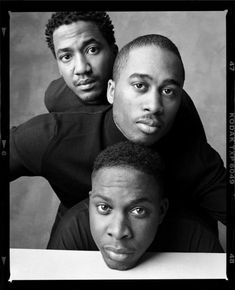 three young men are posing for a black and white photo in front of a gray background