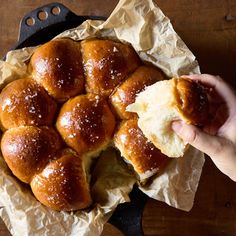 a person holding a piece of bread in front of it on top of wax paper