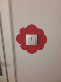 a white door with a red flower painted on the side and a light switch in the middle