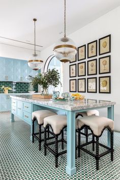 a kitchen with blue cabinets and white stools in front of a marble top table