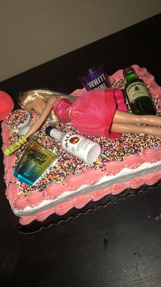 a barbie doll laying on top of a pink cake covered in sprinkles