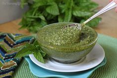 a green smoothie in a small bowl on a plate with a straw sticking out of it