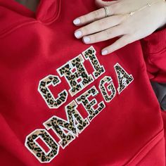 a woman's hand on the back of a red sweatshirt with leopard print letters