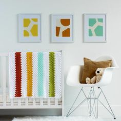 a baby's room with a crib, chair and pictures on the wall