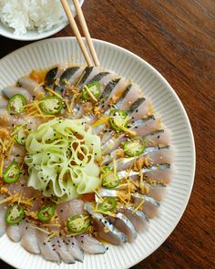 a white plate topped with sushi and rice next to chopsticks on a wooden table