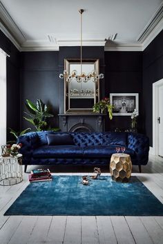 a living room with black walls, blue couches and rugs on the floor