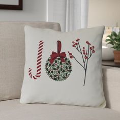 a white pillow with a christmas wreath and candy canes on it sitting on a couch