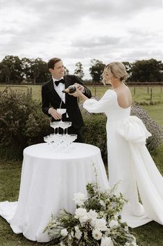 a man and woman standing next to each other in front of a table with a cake on it