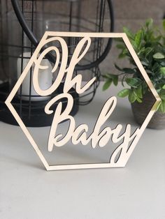 a wooden cutout with the words oh baby on it next to a potted plant