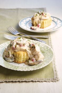 two plates topped with food on top of a green table cloth next to silverware