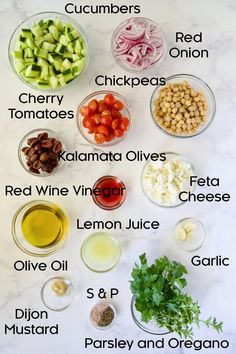 the ingredients to make this salad are displayed on a white marble counter top, including olives, cucumbers, cherry tomatoes, chickpeas, kale and red onions