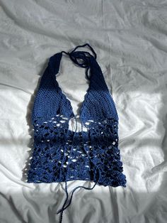 a blue crocheted scarf laying on top of a white bed spread with it's fringed edges