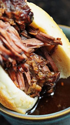 a close up of a sandwich with meat and sauce in a bowl on a table