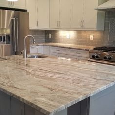 a kitchen with an island and stainless steel appliances in the center, along with marble countertops