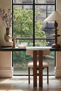 a dining room table with two chairs and a lamp in front of a large window