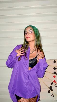 a woman with green hair wearing a purple shirt and fishnet stockings posing for the camera