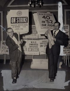 two men standing next to each other in front of signs