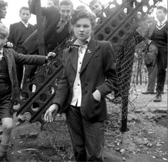 a group of children standing next to each other in front of a wire fence and net