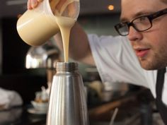 a man pours some liquid into a blender to make something delicious and tasty