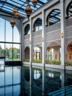 an indoor swimming pool with chandeliers hanging from it's ceiling and windows