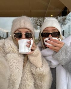 two women in winter clothing holding coffee mugs