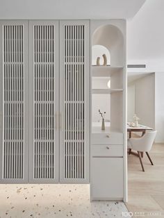 an open closet with white walls and doors in the center, along with a dining room table