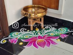 a gold bowl sitting on top of a floor next to a wooden chair and door