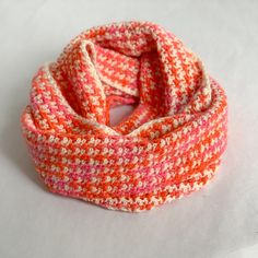 an orange and white knitted scarf on a white surface