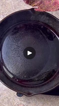 a black cast iron skillet sitting on top of a stone floor next to a leaf